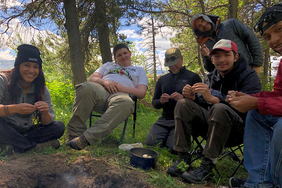 Blackfeet youth sitting around a fire pit