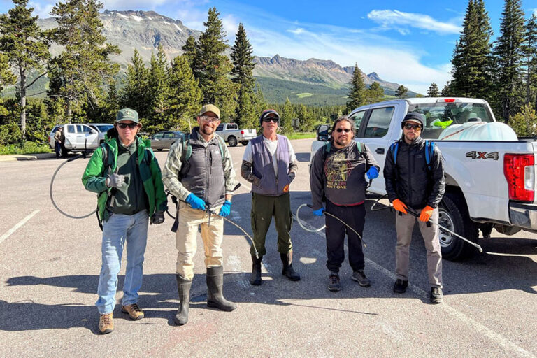 A group of volunteers pose with herbicide sprayers before a noxious weed event