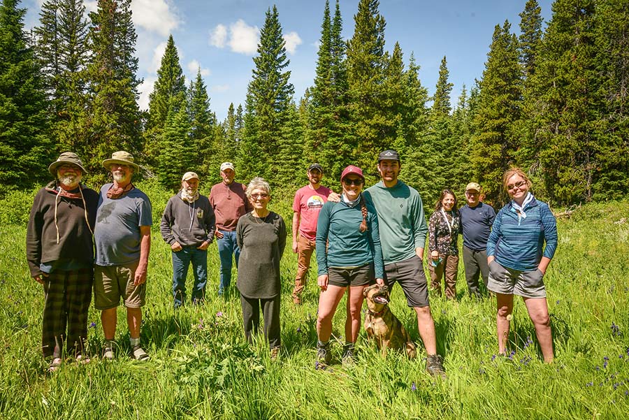 A group of hikers pose in a green meadow