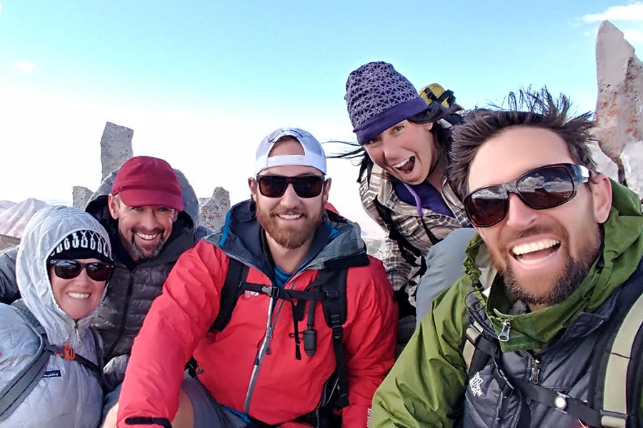Five friends smiling during a winter hike