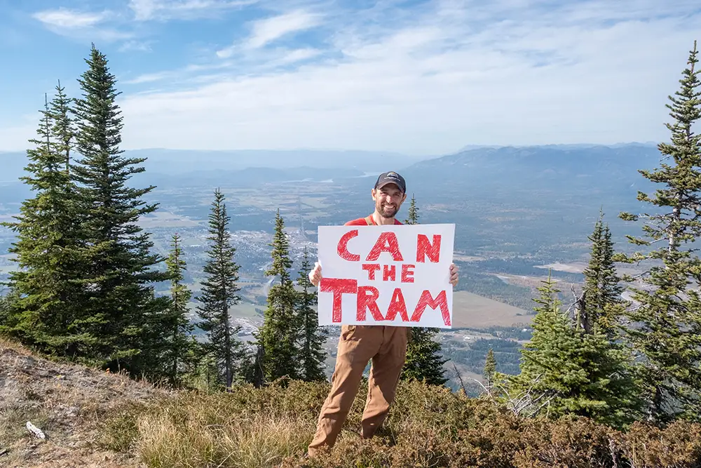 GTMA Executive Directors holds a "Can the Tram" sign while standing in the proposed site of Pursuit Hospitality's tourist tram